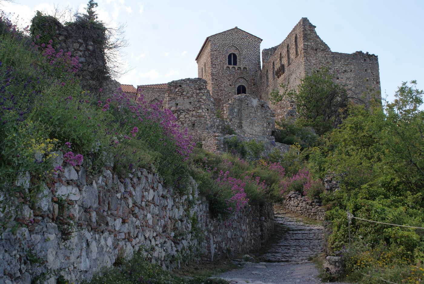A ruined building above the path, with the spring flowers out.
