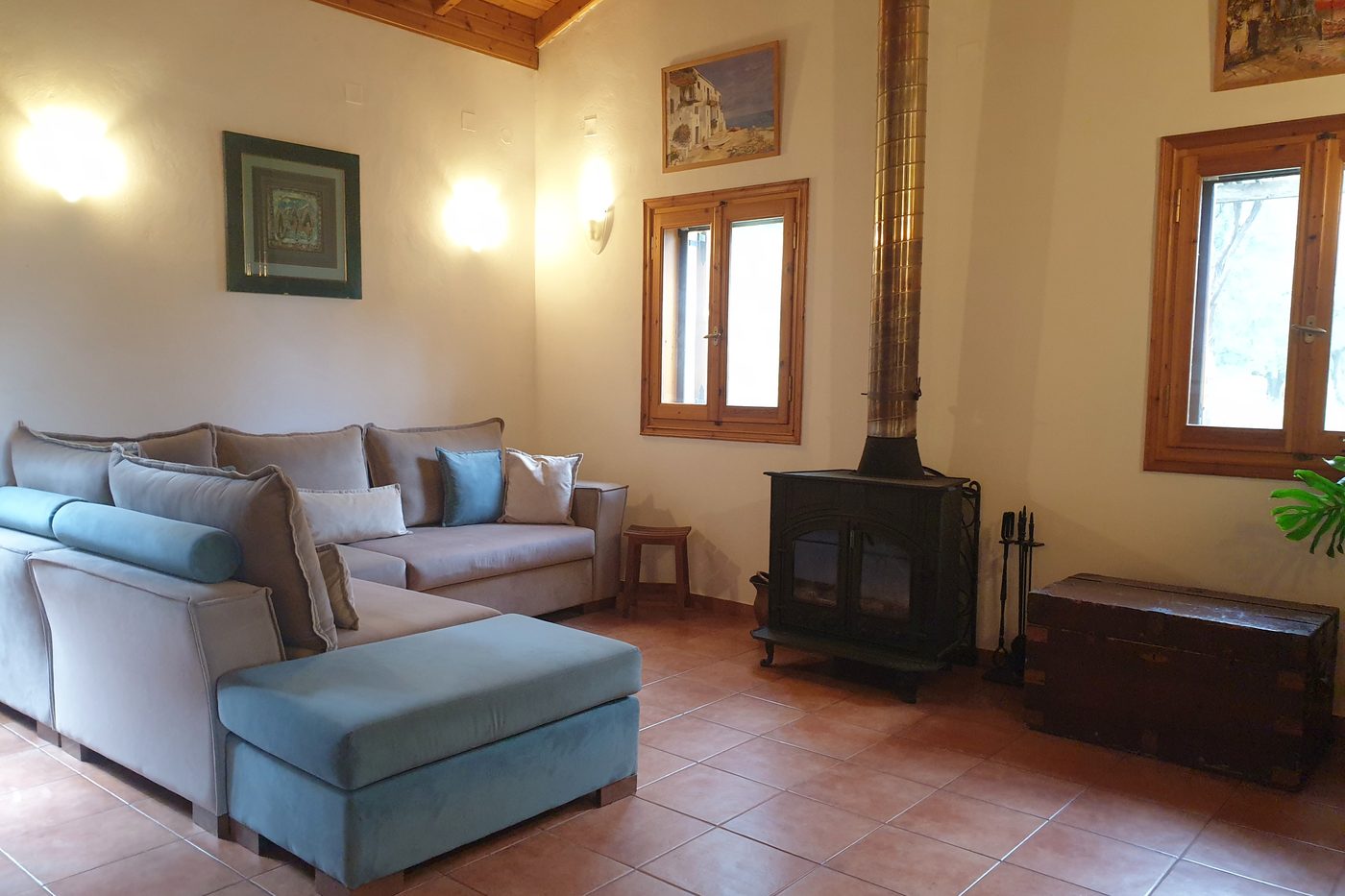 The sitting room at The Olive Farm, with the sofa, the wood-burning stove and the tiled floor.