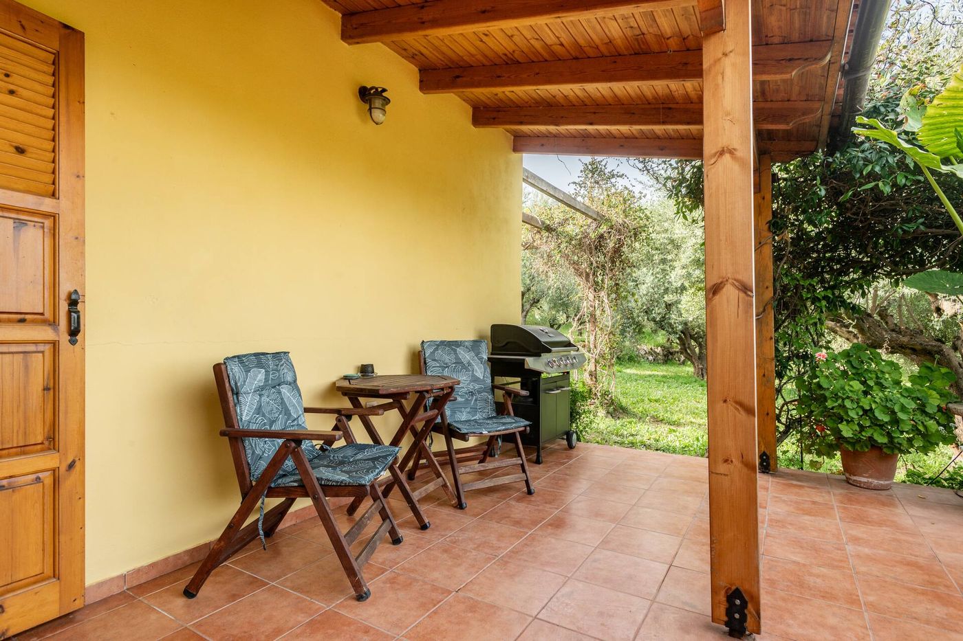 Two chairs, a small table and the barbecue at the far end of the veranda.