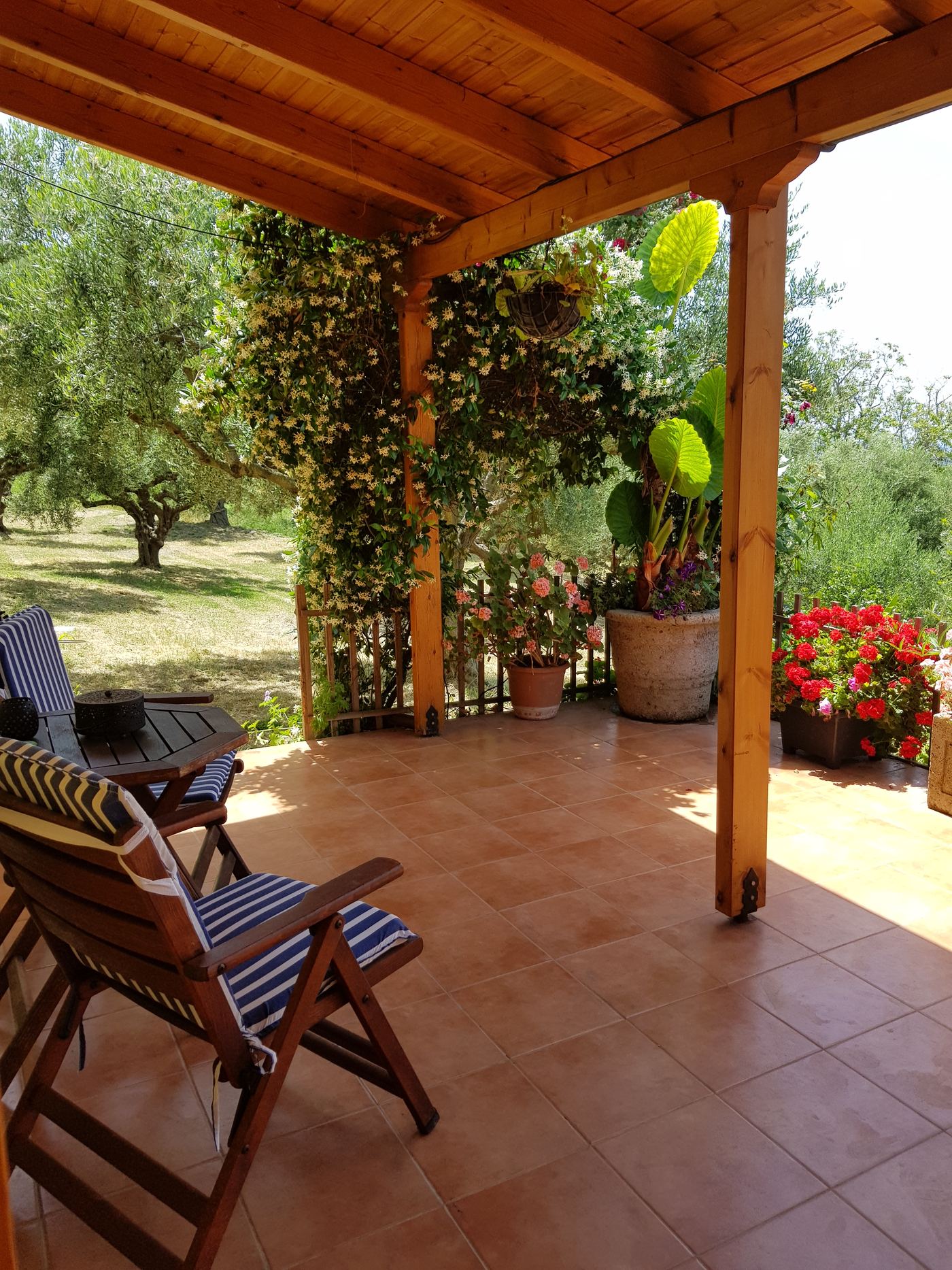 Deck chairs and a small table on the tiled veranda.